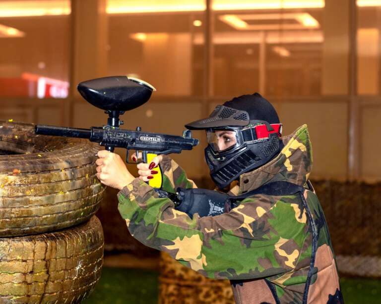 Two players in skull masks at the Battle Zone logo wall