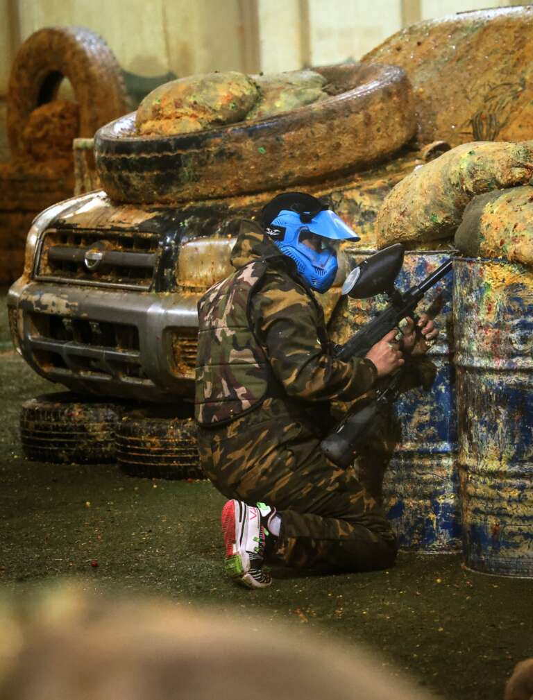Two players in skull masks at the Battle Zone logo wall