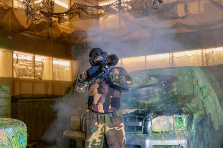 Two players in skull masks at the Battle Zone logo wall