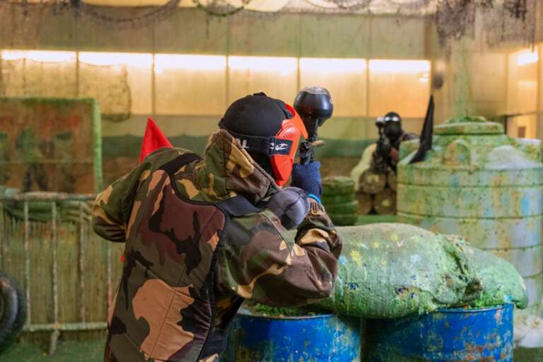 Player in camo taking cover by the barrels