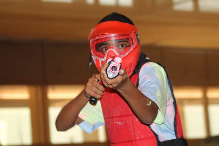 Masked birthday kid aiming a kids’ marker