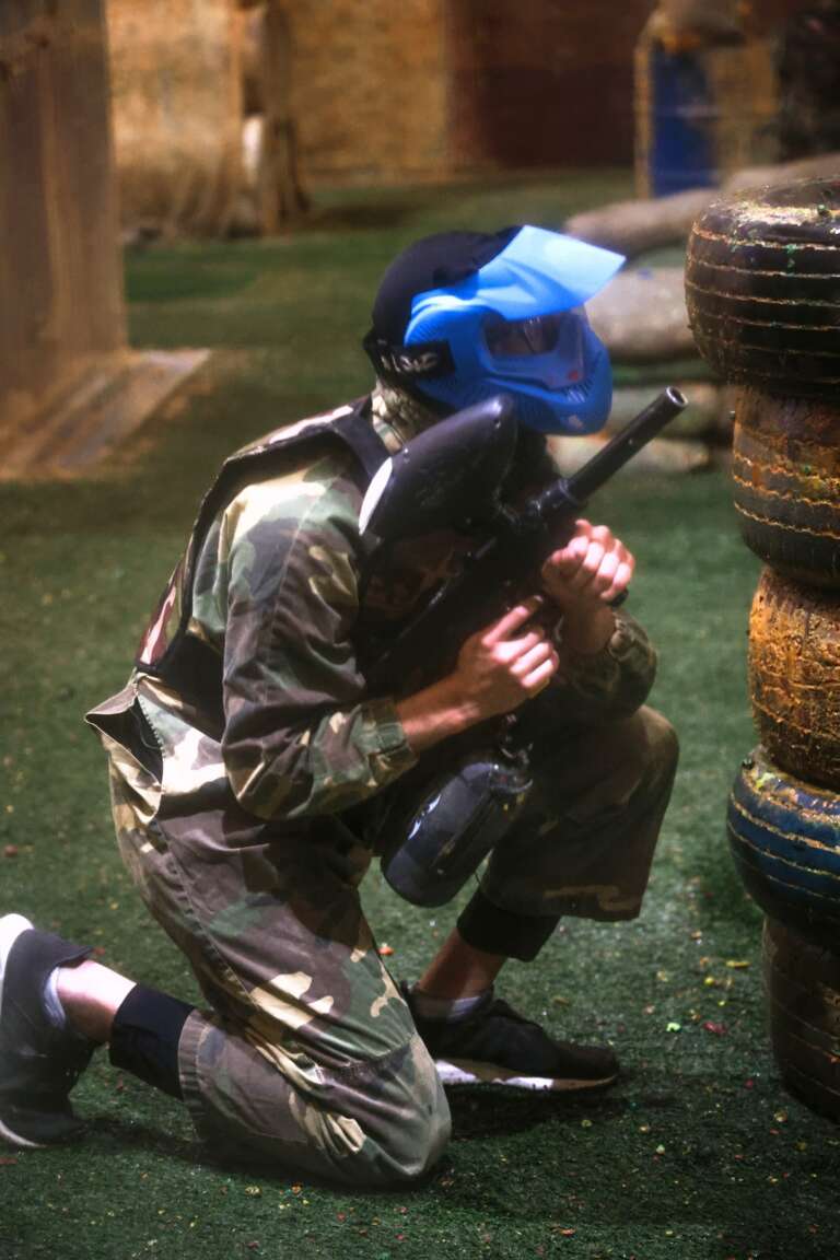 Player in a blue mask kneeling by the tyre wall