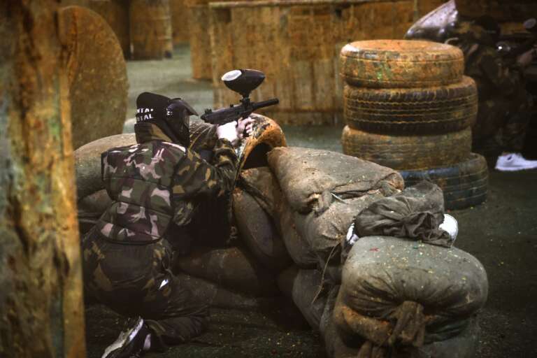 Player behind sandbags in full camo gear