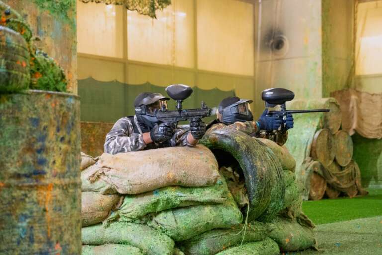 Two players in skull masks at the Battle Zone logo wall